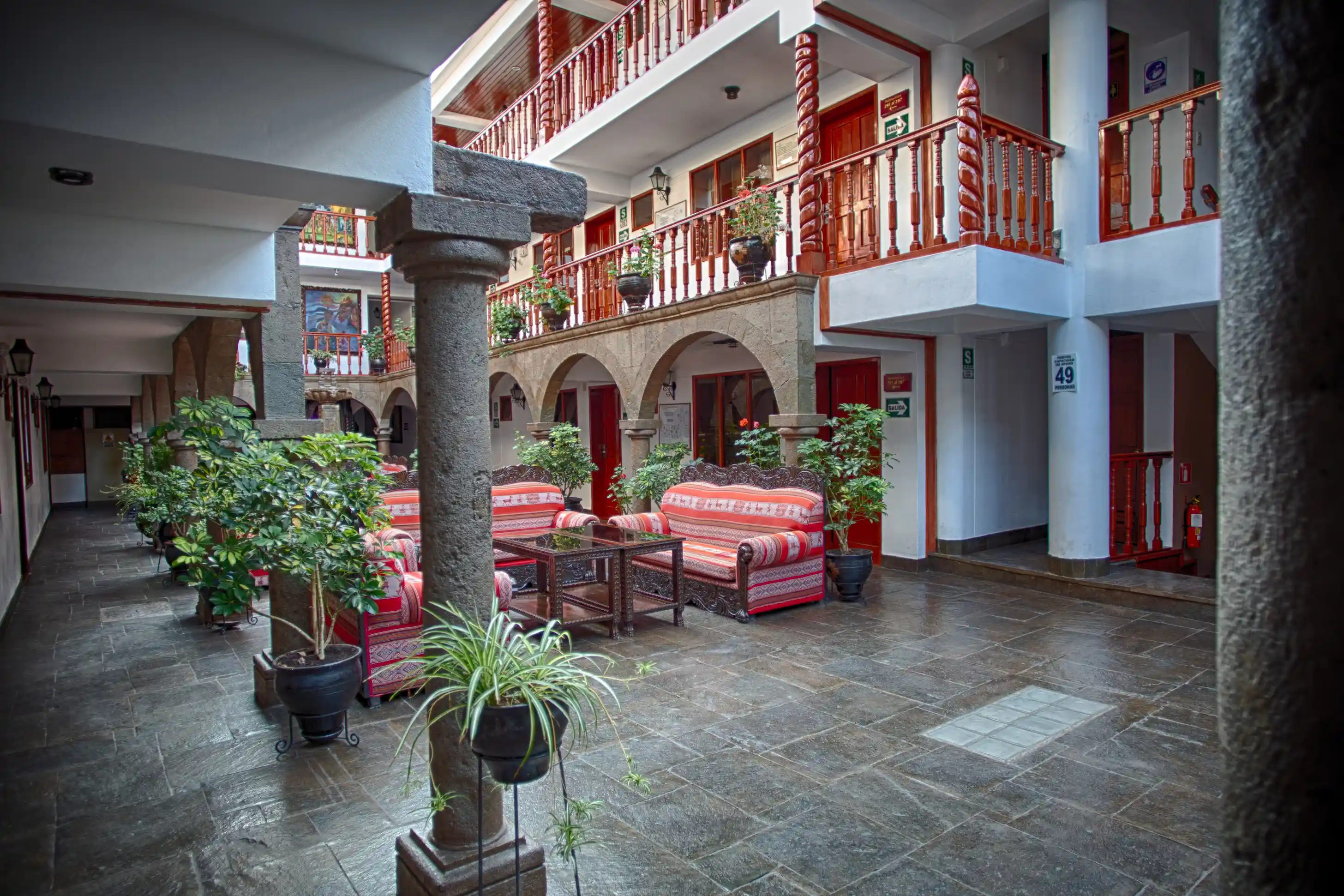 El lobby de Munay Wasi Inn en Cusco, que muestra elegante arquitectura colonial con cálidos detalles de madera y acogedoras áreas de descanso.